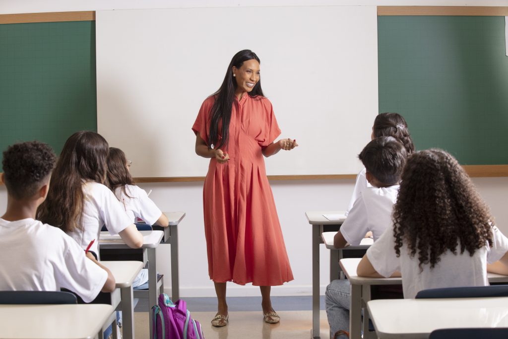 Texto blog - Dicas para contratação de professores A contratação de professores é sempre um desafio! Mas fique tranquilo, que com um bom planejamento, é possível encontrar o profissional ideal. Além de identificar profissionais com as competências técnicas necessárias, é fundamental que os valores e o estilo de trabalho do candidato estejam alinhados à cultura da instituição. Um processo seletivo mal estruturado aumenta o risco de contratação de profissionais que não se adaptem ao ambiente ou às funções, gerando desperdício de tempo, dinheiro e, muitas vezes, afetando o clima da equipe. Por isso, investir em uma seleção bem estruturada faz toda a diferença! Sendo assim, quero compartilhar algumas dicas que podem te auxiliar nessa importante missão: Contratação de professores: o que devo fazer? (H2) Defina o perfil ideal para a vaga (H3) Na contratação de professores, é essencial ter clareza sobre as competências necessárias para a função. Liste as atividades que o novo professor realizará e destaque o que é indispensável e o que é desejável no perfil. Muitas vezes buscamos perfis “super-heróis”, com qualificações que não serão usadas no dia a dia, pois isso pode dificultar a seleção e gerar frustrações tanto para a escola quanto para o profissional. Ou seja, o ideal é ter uma descrição clara e objetiva, para ajudar a atrair os candidatos certos! Divulgue a vaga com eficiência (H3) Deixe que saibam que você está contratando! É preciso que a oportunidade chegue às pessoas certas, por isso, publique a vaga no site, em plataformas especializadas e aproveite suas redes de contato para ampliar o alcance. Ah, esteja sempre aberto para indicações, elas são sempre uma boa fonte, porém devem ser avaliadas da mesma forma que os demais candidatos. Uma divulgação estratégica faz toda a diferença para atrair os melhores talentos! Estruture o processo de contratação de professores (H3) Desenhe o processo seletivo e prepare um cronograma. A partir do perfil que você definiu, pense em ferramentas que podem te apoiar na identificação e avaliação das competências necessárias, como por exemplo: Testes técnicos Aulas teste Videoaulas Deixe claro para o candidato quais serão as etapas, assim como o cronograma de todo o processo seletivo. Etapas online são ótimas também, podem ajudar na otimização do tempo e recurso, tanto sua quanto dos pretendentes para a vaga. A entrevista: o ponto alto da contratação de professores (H3) Dê espaço para o candidato falar e compartilhar exemplos de experiências. Ao final, pergunte se ele gostaria de complementar algo e abra para que ele também faça perguntas. Assim, a conversa se torna mais produtiva e transparente! A entrevista é a cereja do bolo, o momento pela qual você e o candidato se preparam nas etapas anteriores do processo seletivo. Organize o tempo de conversa e local para esse encontro, seja presencial ou online. É muito comum que o candidato esteja nervoso, deixe-o à vontade, use os primeiros minutos da entrevista para “quebrar o gelo”, porque quanto mais à vontade o profissional estiver, mais natural serão as respostas e comportamentos dele durante a entrevista. Tenha um roteiro de perguntas focado nas competências necessárias para a vaga, especialmente se tiver mais de um candidato nesse processo, pois permite que você tenha uma “régua de avaliação”. Evite perguntas irrelevantes ou muito pessoais; concentre-se em aspectos relacionados somente à função. Dê espaço para o candidato falar e compartilhar exemplos de experiências. Ao final, pergunte se ele gostaria de complementar algo e abra para que ele também faça perguntas. Assim, a conversa se torna mais produtiva e transparente. Dica extra (H3) Lembre-se: durante o processo seletivo, você avalia o candidato, mas ele também avalia você, a instituição e a oportunidade. Seja transparente e mostre o que torna sua escola uma boa oportunidade.